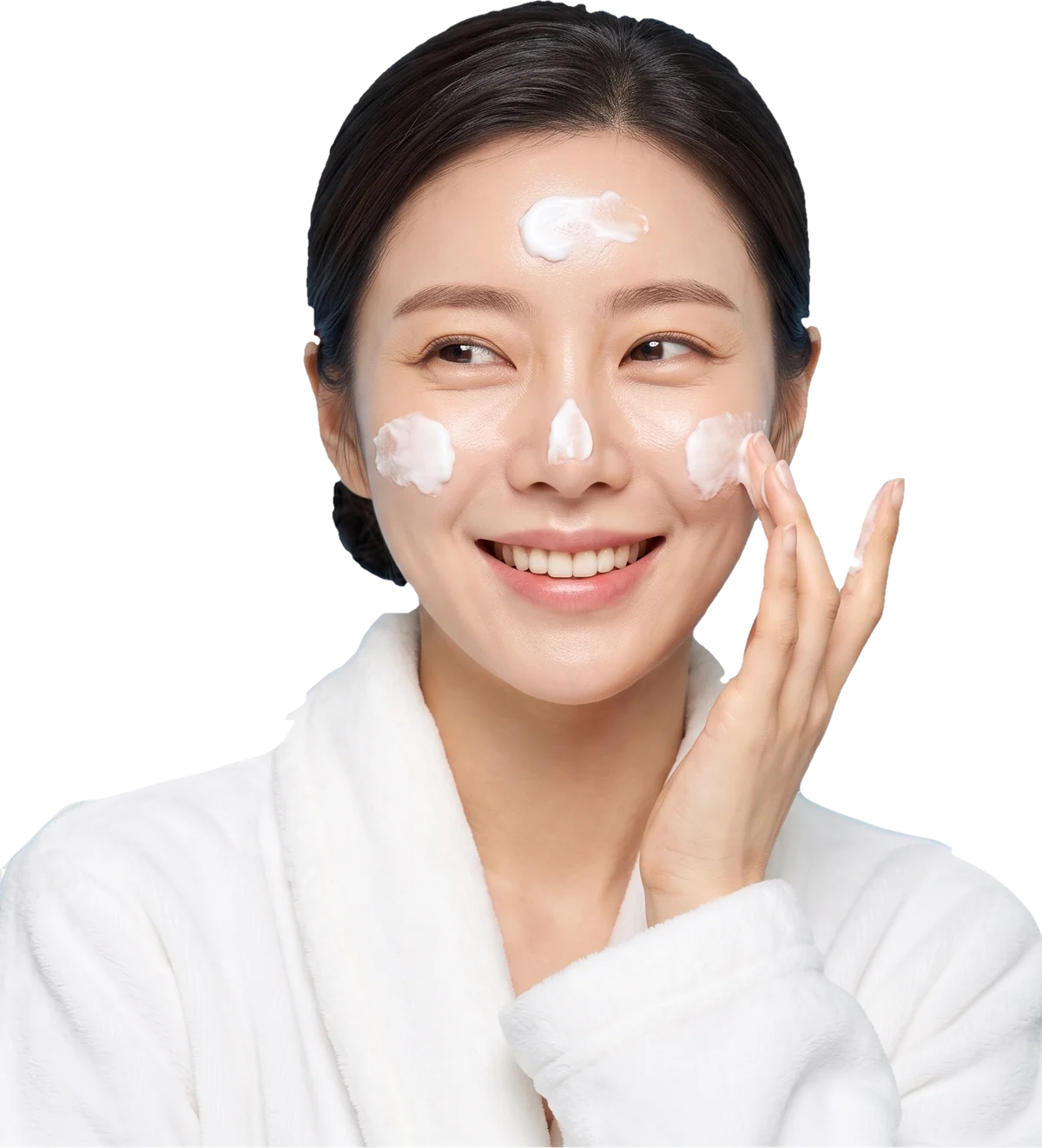 Woman in a white robe smoothing moisturizer onto her cheek